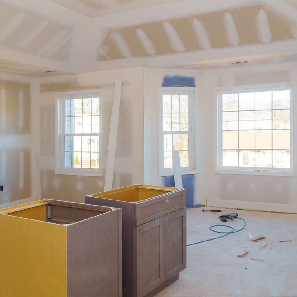 Finishing putty in the room drywalls with plasterboards at a residential building under construction