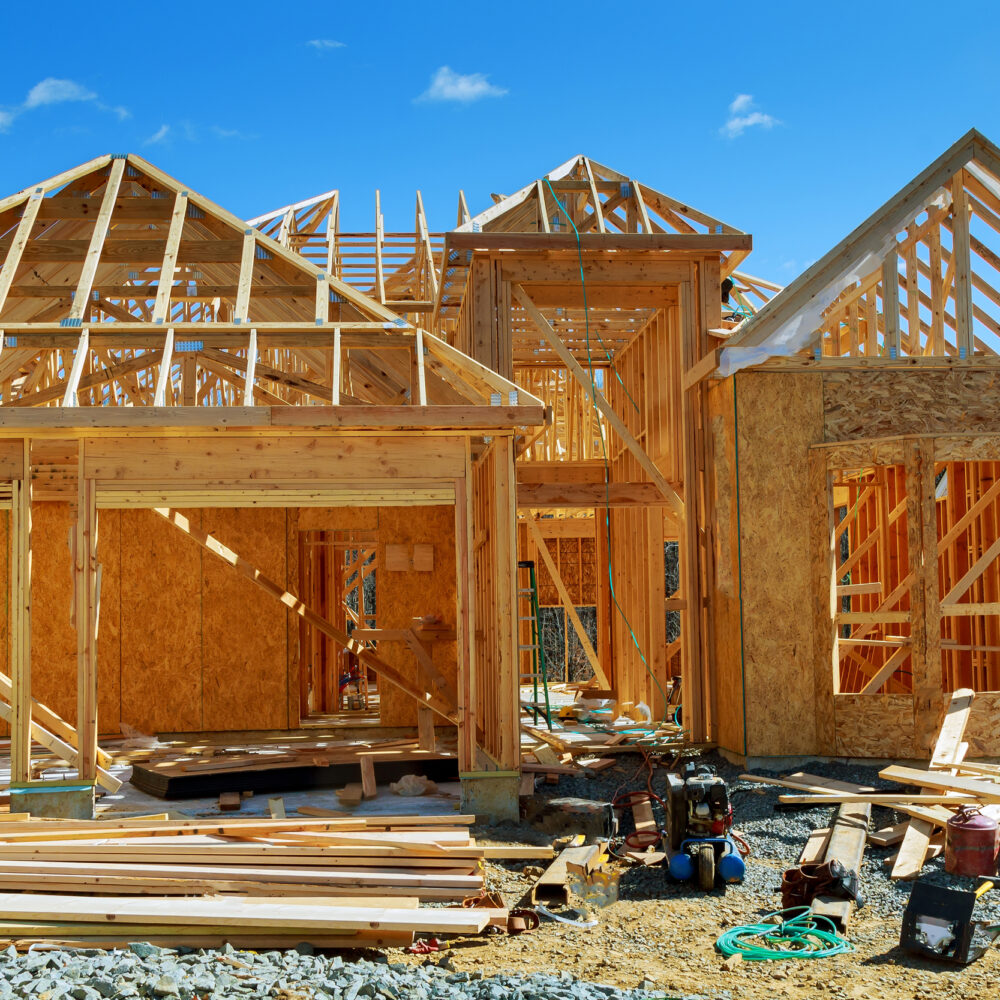 Frame house construction. View on new building with crane against blue sky